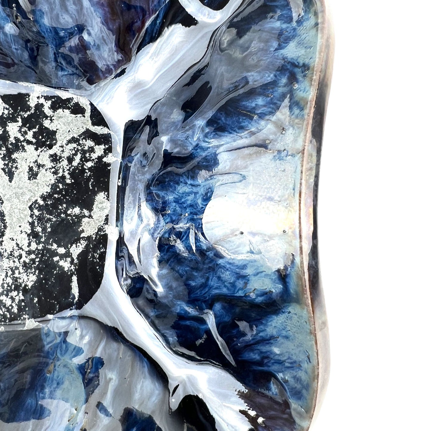 Close-up of the glossy dark blue and silver accents on a handmade medium-sized ceramic bowl.