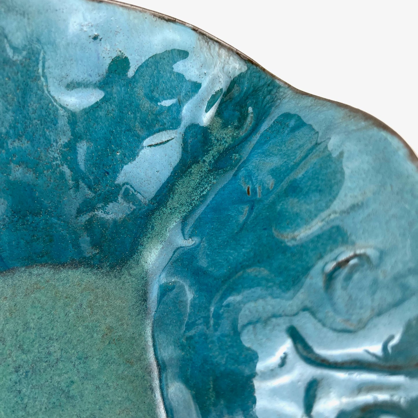 Close-up of the glossy turquoise interior of a handmade medium-sized ceramic bowl.
