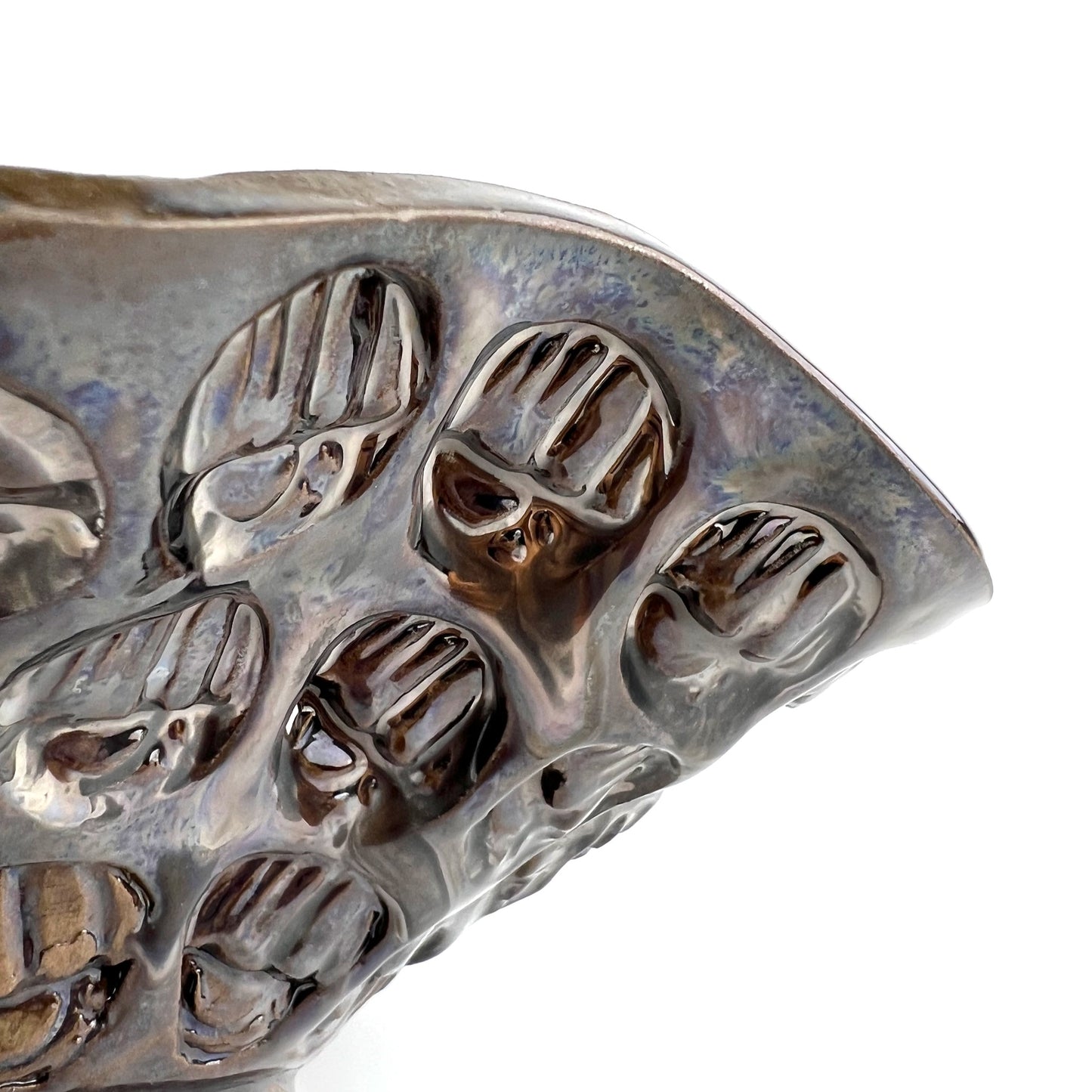 Close-up of the textured hand exterior with dark metallic glaze on a handmade small ceramic bowl.
