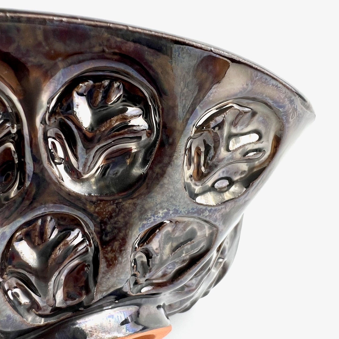 Close-up of the textured tree exterior with dark metallic glaze on a small-sized handmade ceramic bowl.