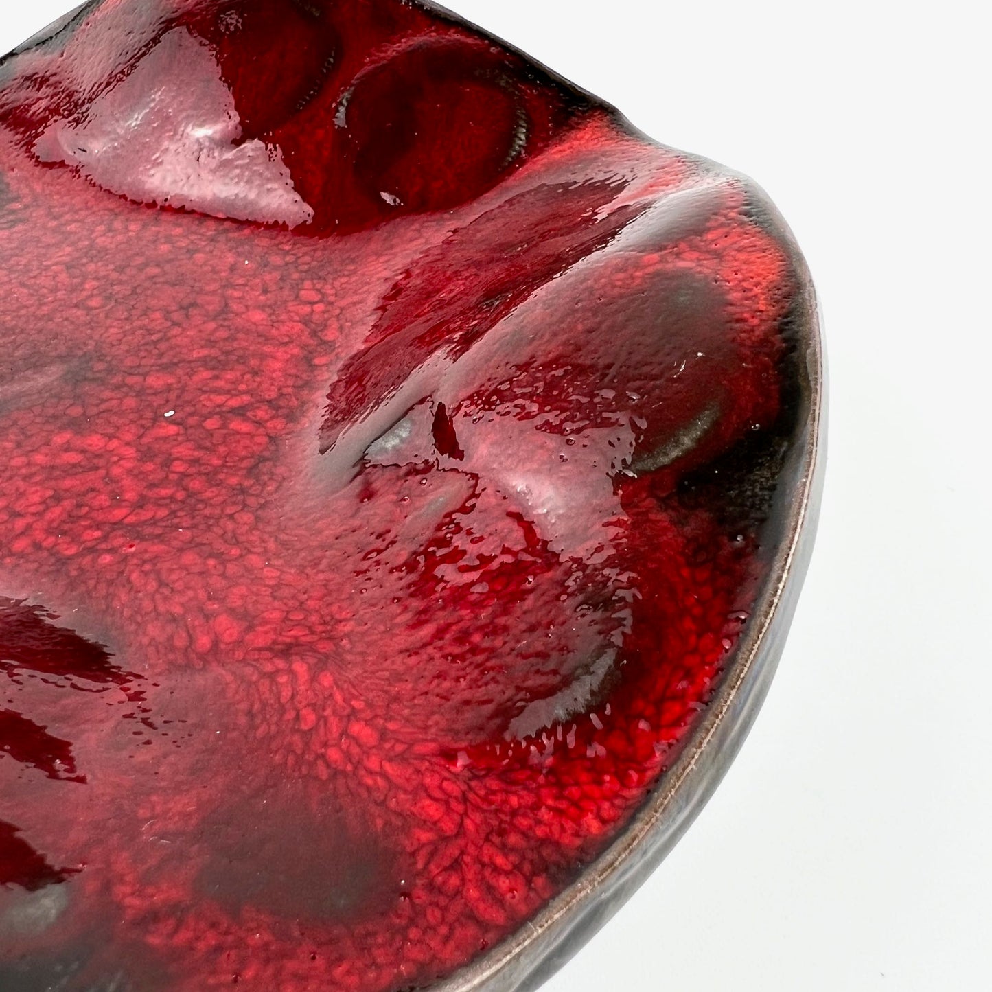 Close-up of the glossy rich red interior of a handmade small-sized ceramic bowl.