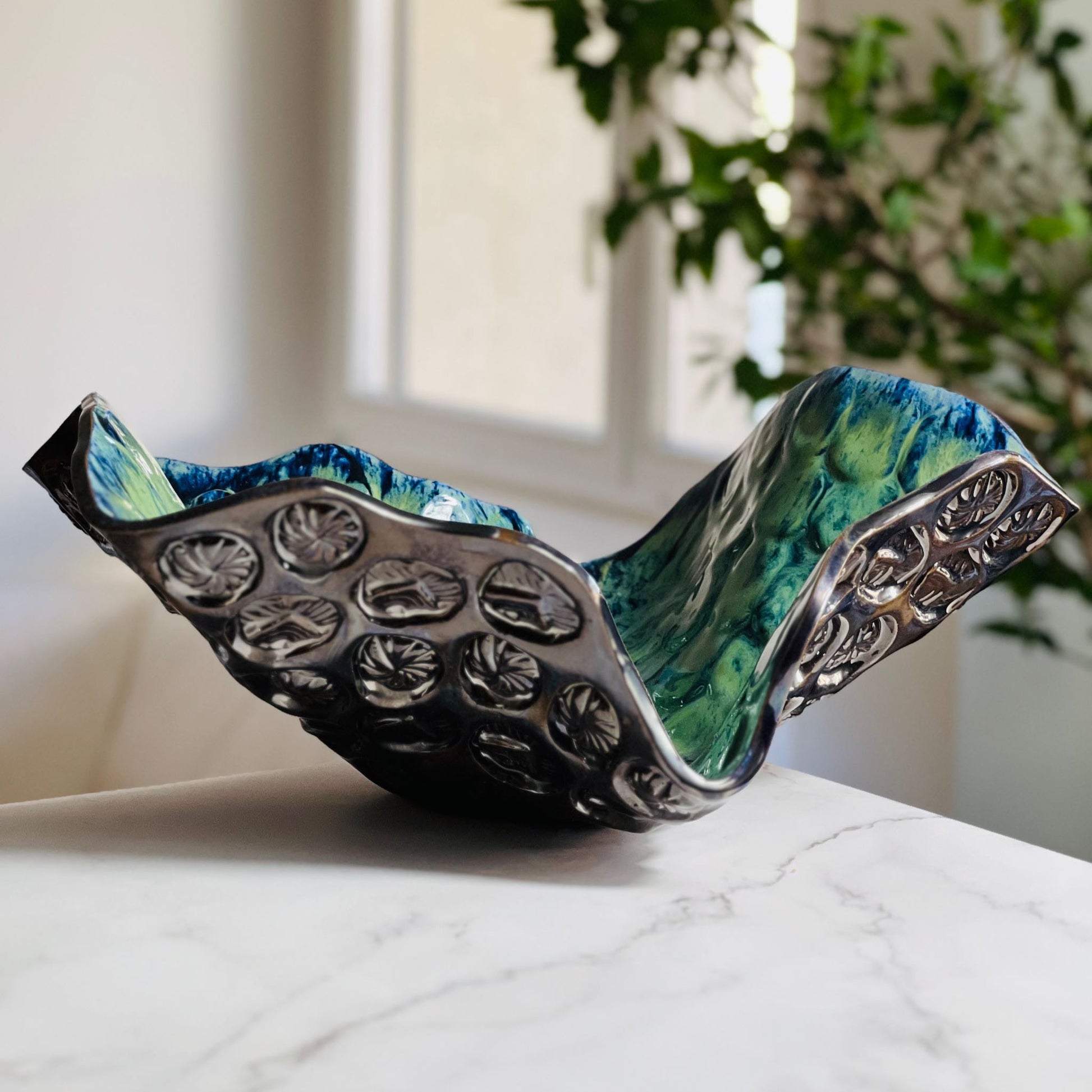 Handmade extra-large decorative cornflower blue ceramic bowl with sunshine texture displayed on a marble table with a living room background.