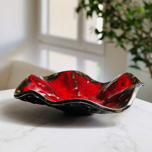 Handmade medium-sized decorative rich red ceramic bowl with beetle texture displayed on a marble table with a living room background.
