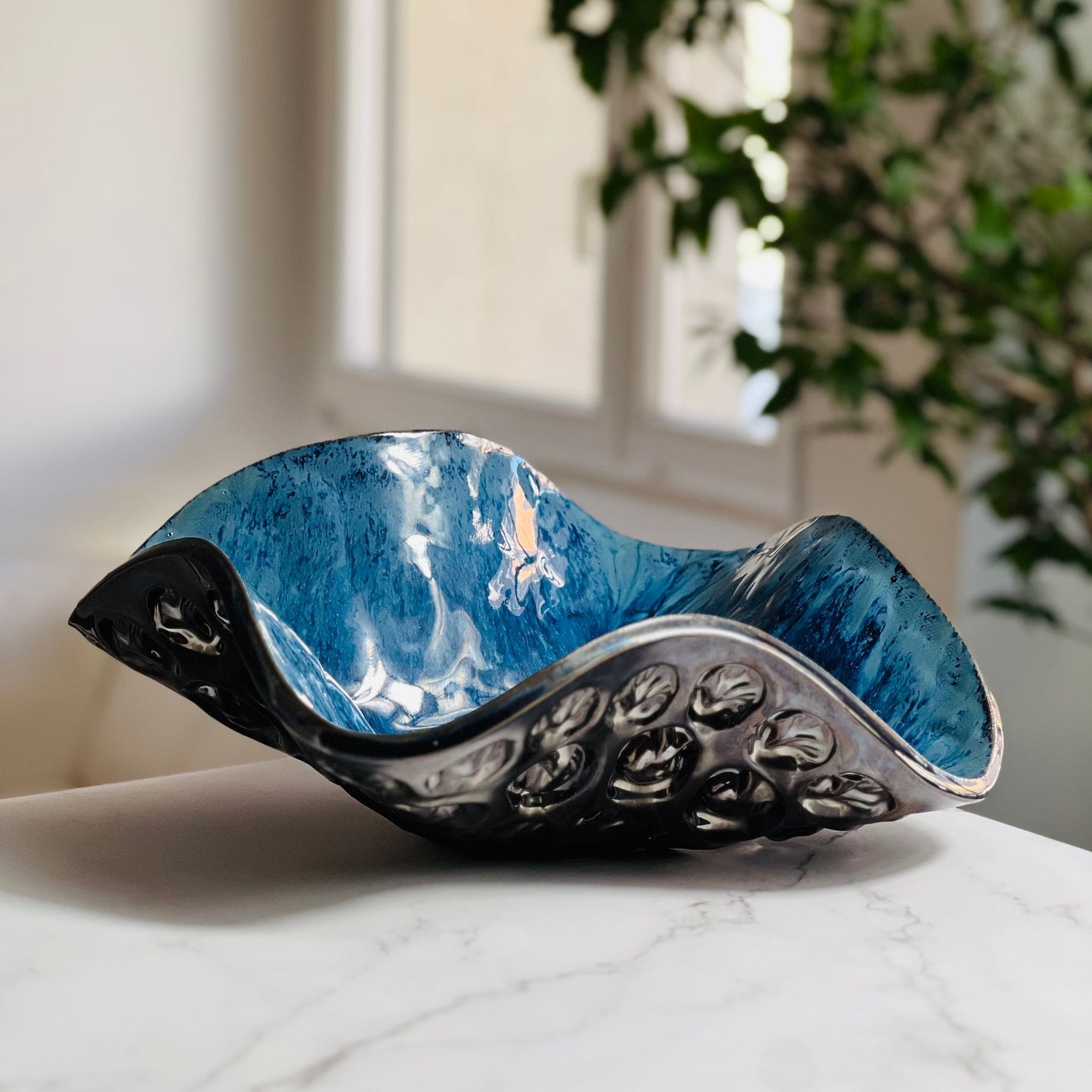 Handmade medium-sized decorative royal blue ceramic bowl with Tree and Ant texture displayed on a marble table with a living room background.