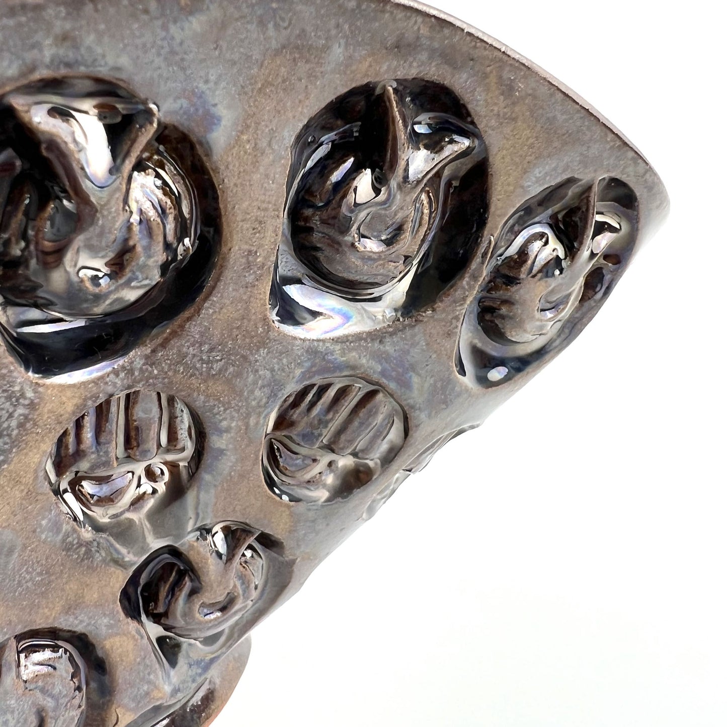 Close-up of the textured hand and ant exterior with dark metallic glaze on a medium-sized handmade ceramic bowl.