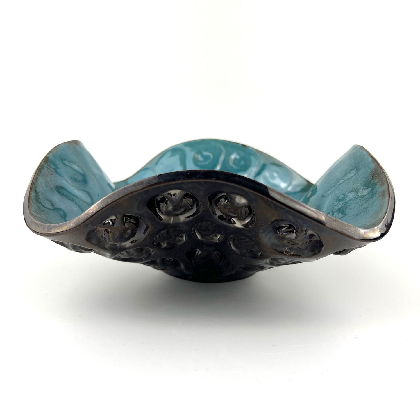 Side view of a handmade medium-sized decorative ceramic bowl featuring a glossy turquoise interior and hand and ant texture design.