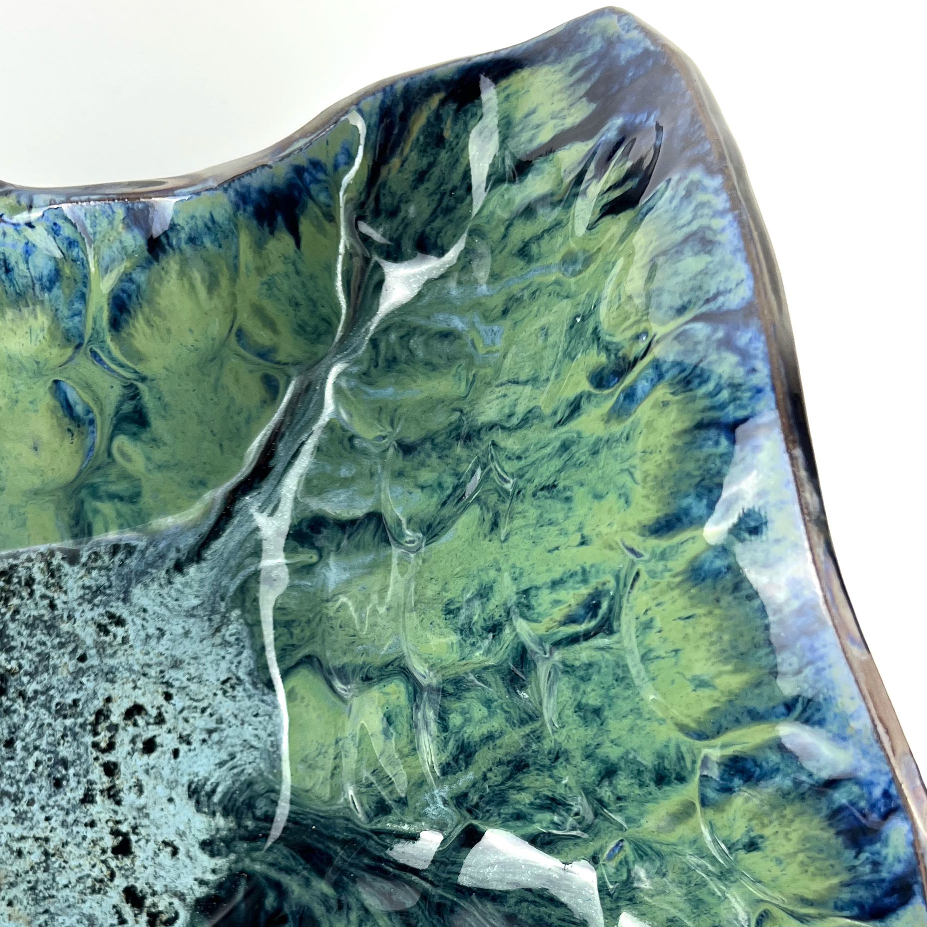 Close-up of the glossy cornflower blue base with navy, seafoam, and lime green accents on a handmade extra-large ceramic bowl.