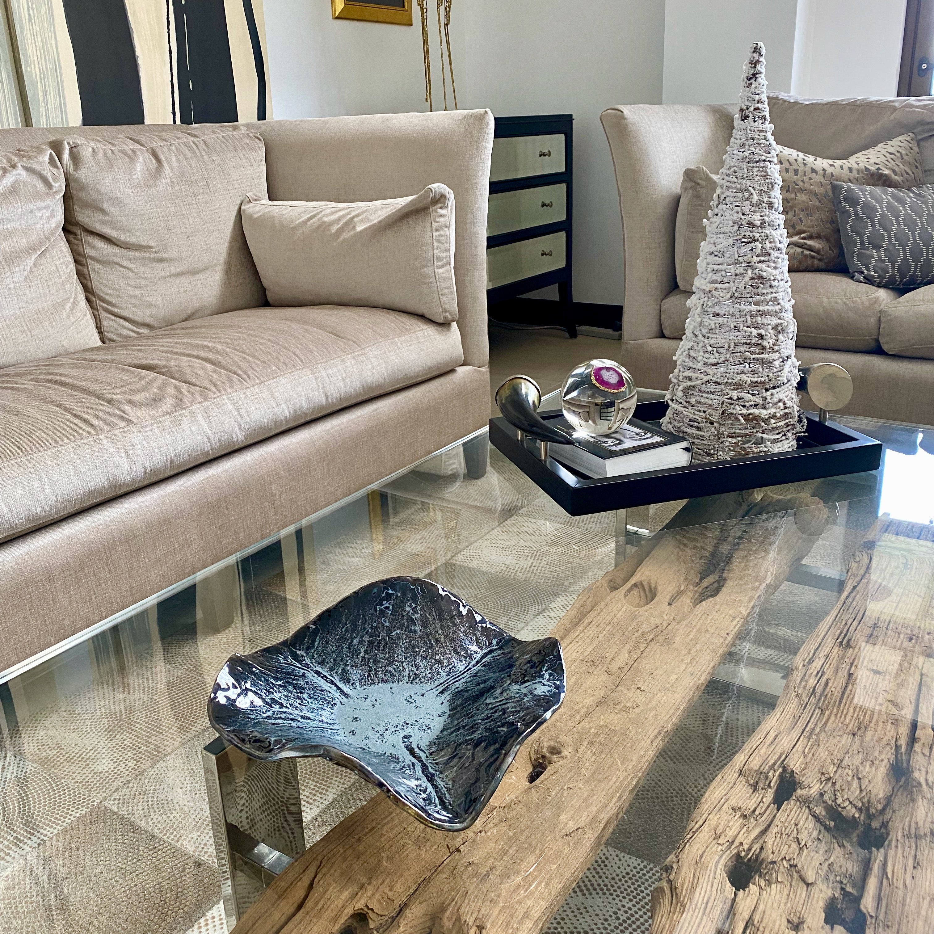 Silver and black ceramic bowl on a glass and wooden coffee table